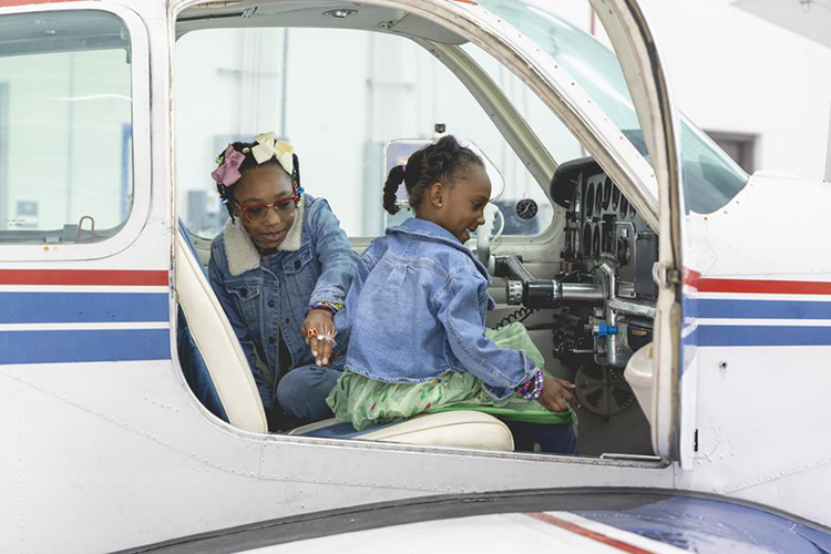 Two young girls inside the cockpit of a small plane